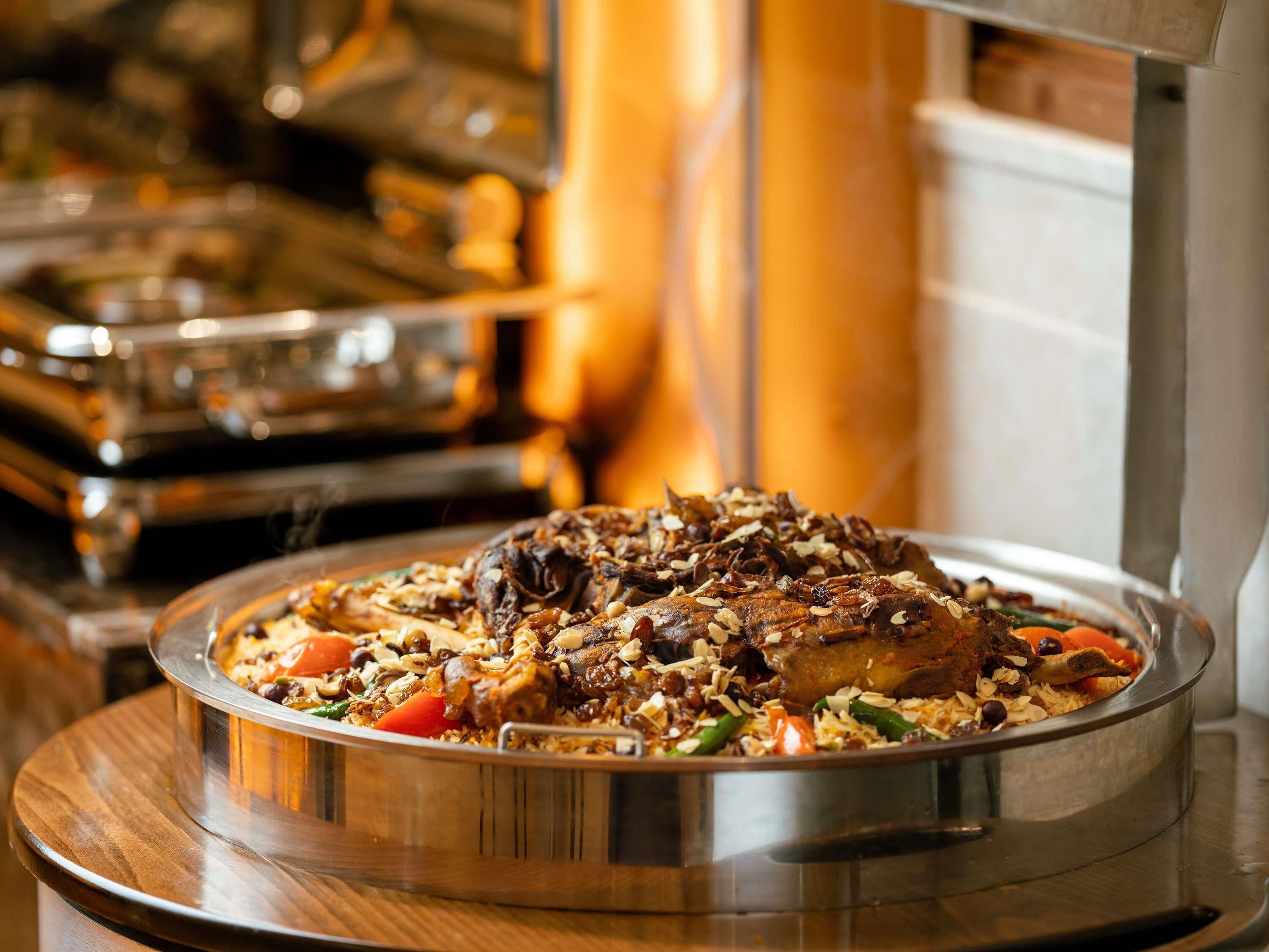 A buffet with a variety of dishes, including rice, vegetables, and meat, served on a large metal platter.