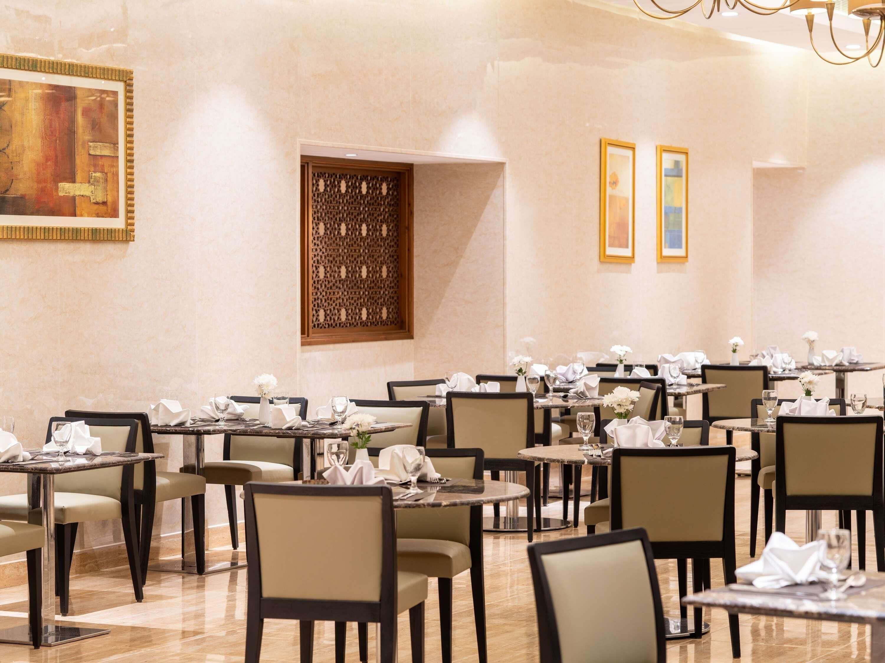 Un espace repas comprenant plusieurs tables, des chaises et un panneau décoratif mural.