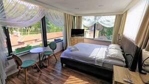 A hotel room with a bed, a TV, a desk with a chair, and a window with curtains. - Romantic Mansion (Istanbul)