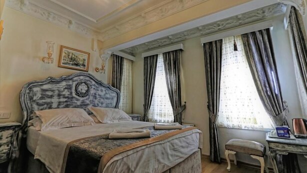 A classic bedroom with a large bed, a small table, and a chair. - Romantic Mansion (Istanbul)