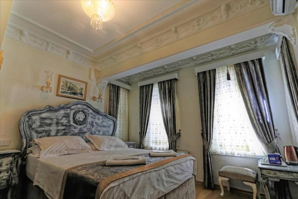 A classic bedroom with a large bed, a small table, and a chair.