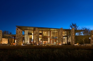 A modern house with large glass windows, stone pillars, and a well-lit interior. - Tierra Atacama, Beckons (San Pedro de Atacama)