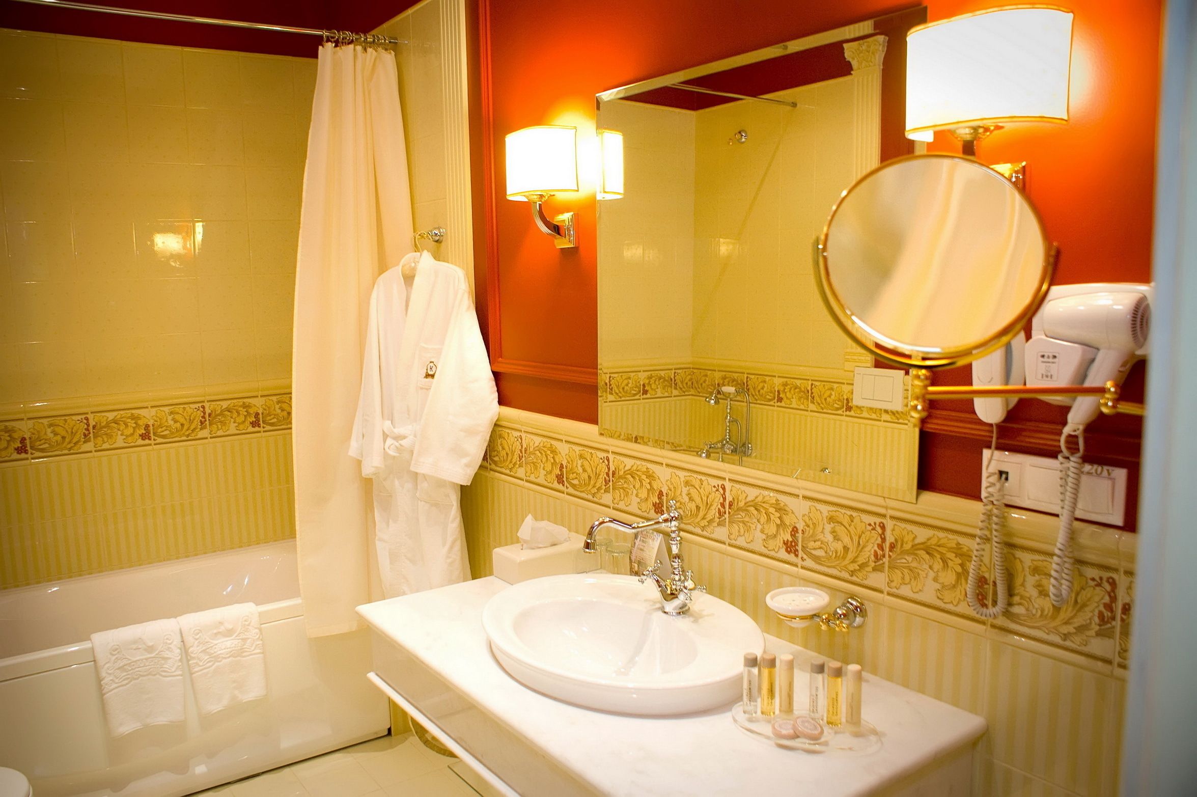 A bathroom with a bathtub, a sink with a mirror, a towel rack, and a hairdryer.