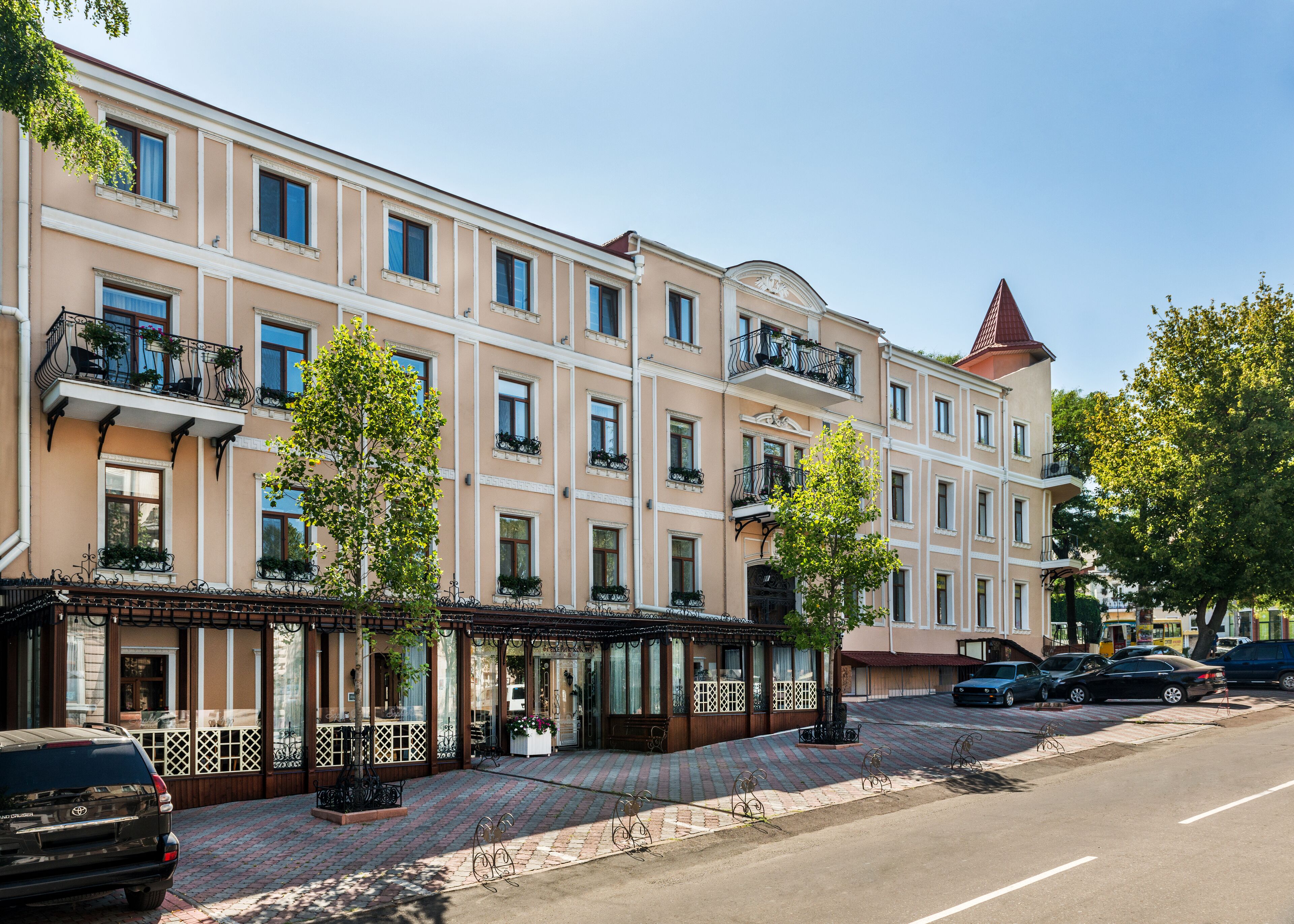 Ein mehrgeschossiges Hotel im klassischen Stil, mit Balkonen, die schmiedeeiserne Geländer und Pflanzgefäße zieren.