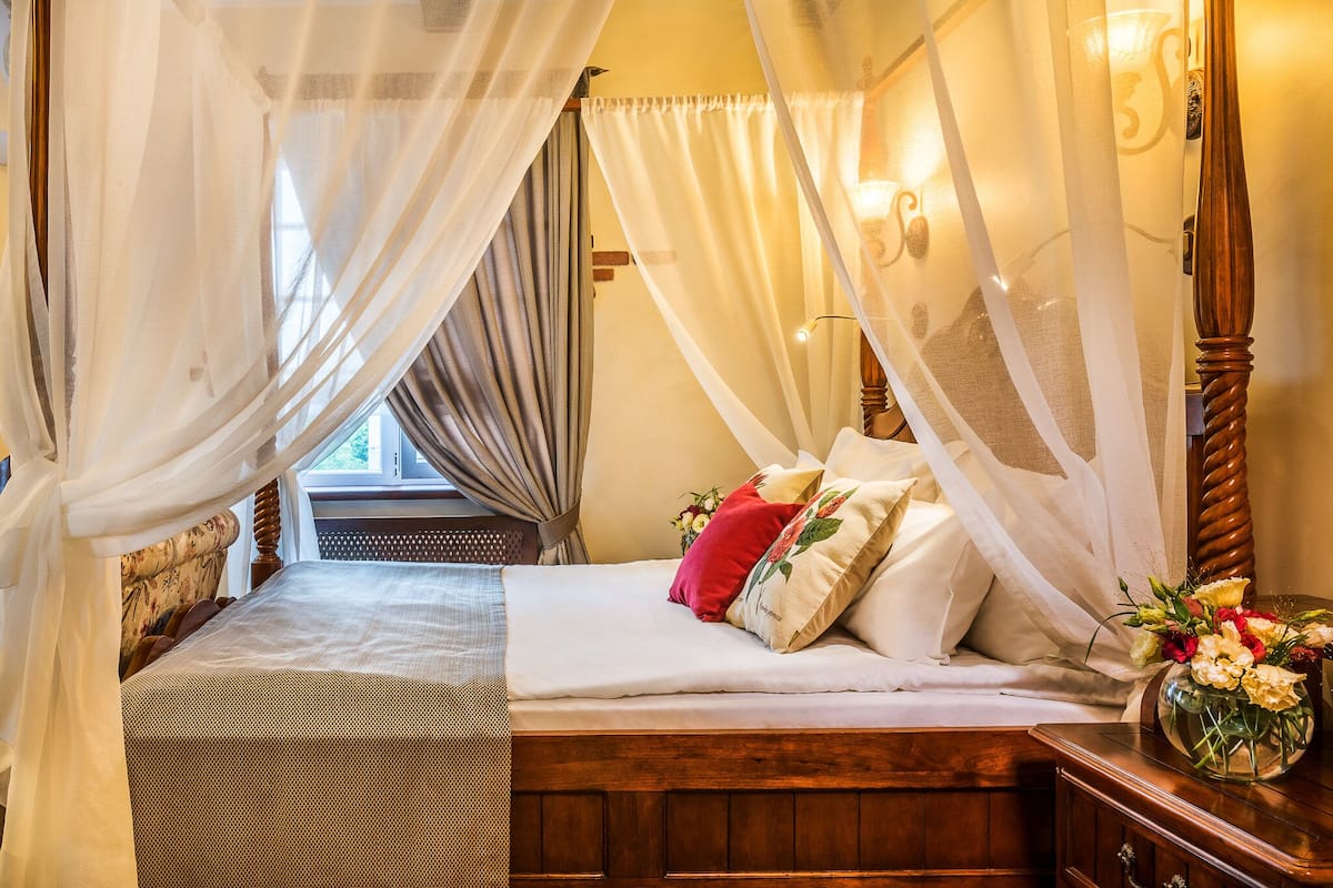 A bedroom with a wooden bed, white bedding, and a canopy.