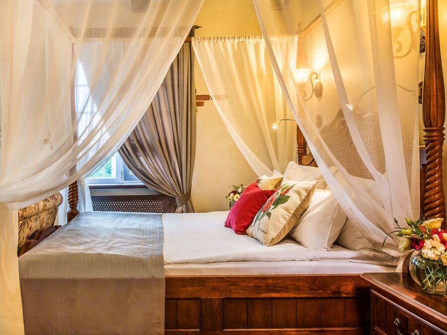 Ein Schlafzimmer mit einem hölzernen Bett, weißer Bettwäsche und einem Baldachin.