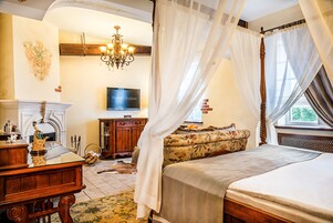 Un dormitorio con una cama, televisor, cómoda de madera, sofá y una araña.