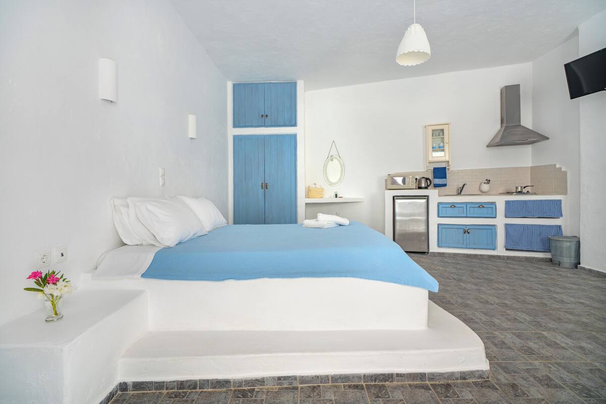 Ein Schlafzimmer mit Bett, einer kleinen Küchenzeile und einem Badezimmer.