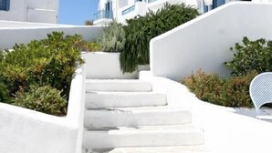 A white staircase leading up to a building with blue balconies, surrounded by greenery. - Castellano Village (Astypalaia)