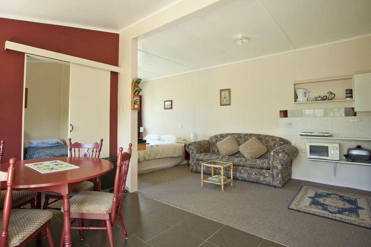 A compact living space with a dining area, a sofa, a small table, and a kitchenette.