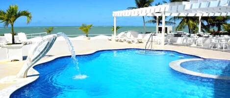 Una piscina al aire libre, sombrillas, sillones reclinables de piscina