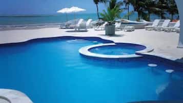 Una piscina al aire libre, sombrillas, sillones reclinables de piscina