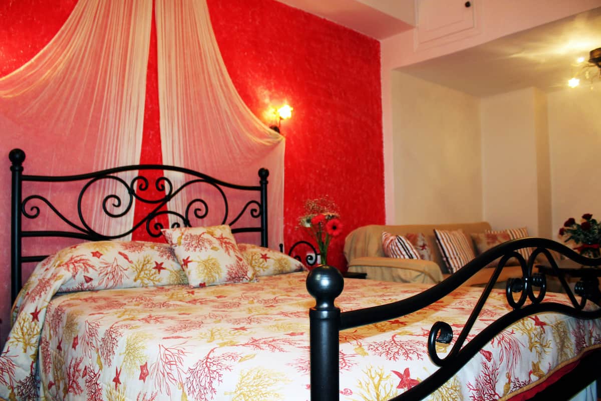 Un dormitorio con cama, dosel y sofá.