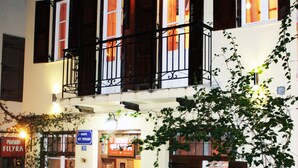 A two-story building with a balcony, potted plants, and a sign indicating a restaurant. - Pension Filyra (Nafplio)