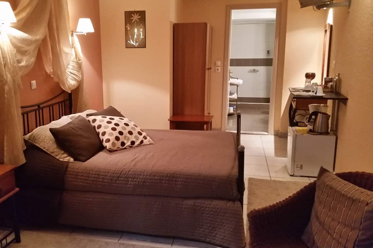 Un dormitorio con cama, mesita de noche, lámpara y vistas al baño.