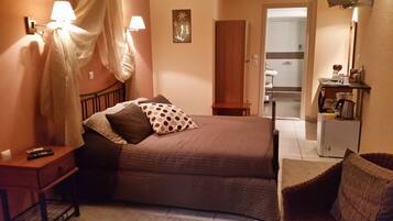 A bedroom with a bed, bedside table, lamp, and a view of the bathroom.