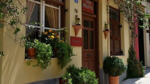 A building with a sign reading "Pension Filyria" and a reception area. There are potted plants and a bench outside. - Pension Filyra (Nafplio)