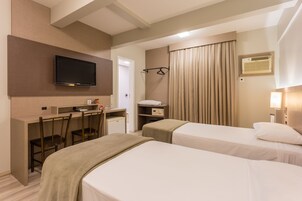 A hotel room with two beds, a desk with a chair, a television, and a wardrobe.