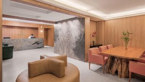 Una moderna hall d'albergo con una reception, un'area salotto e un tavolo da pranzo.