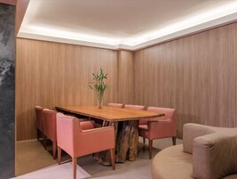 Un comedor moderno con una mesa de madera, sillas rosadas y un centro de mesa con una planta de bambú.