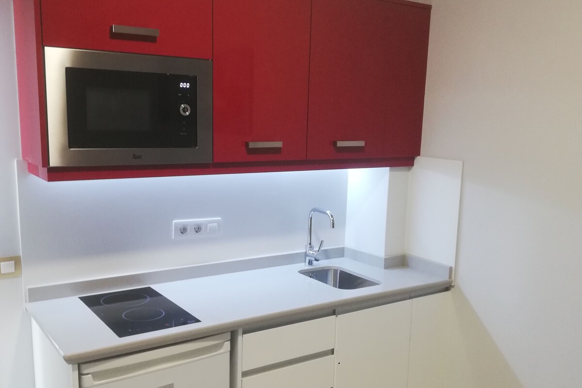 A compact kitchen with a microwave, sink, and integrated dishwasher.