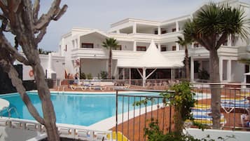 Una piscina al aire libre, sombrillas, sillones reclinables de piscina