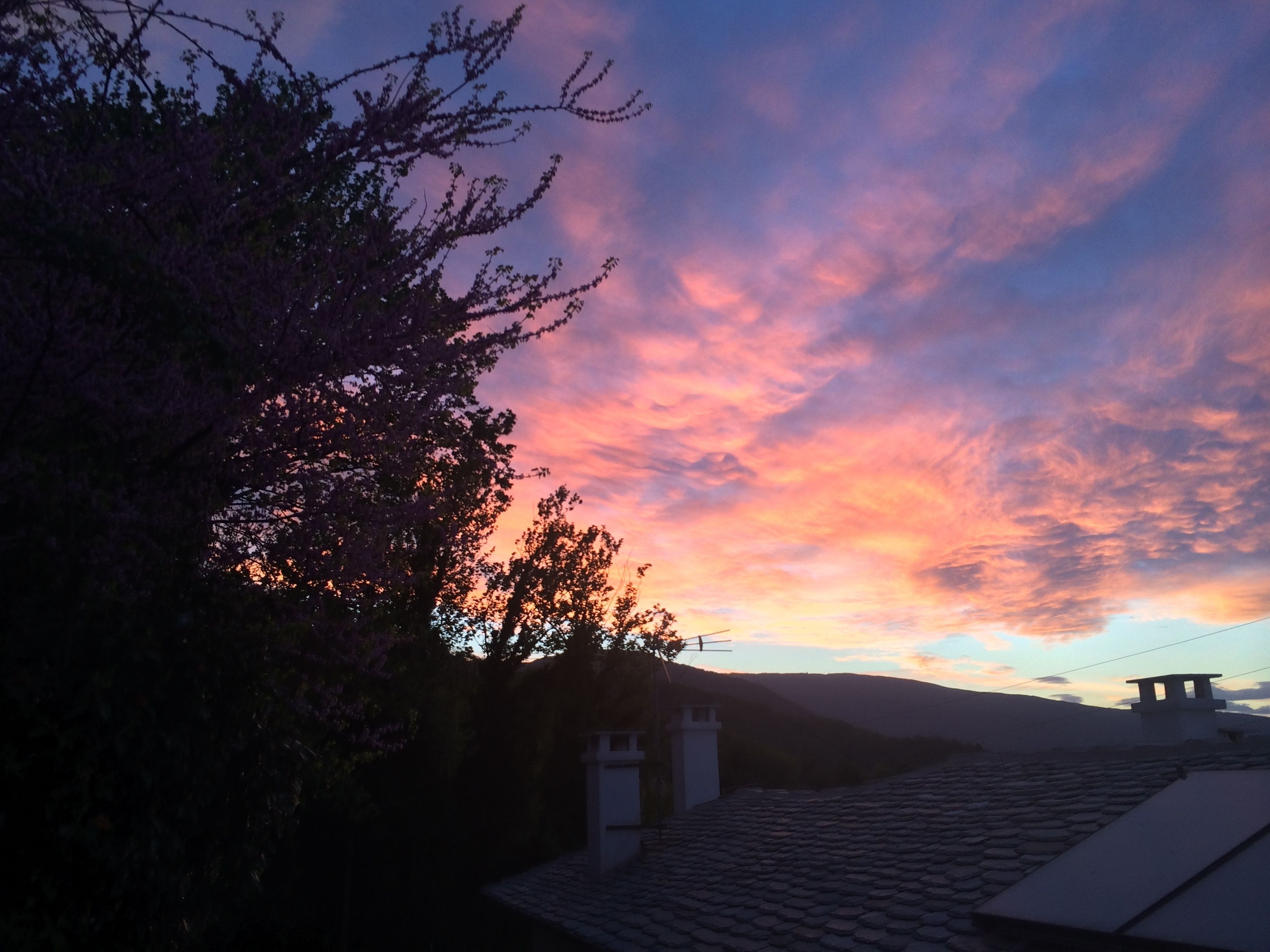A sunset over a residential area with a tiled roof and a stone structure.