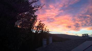 A sunset over a residential area with a tiled roof and a stone structure.