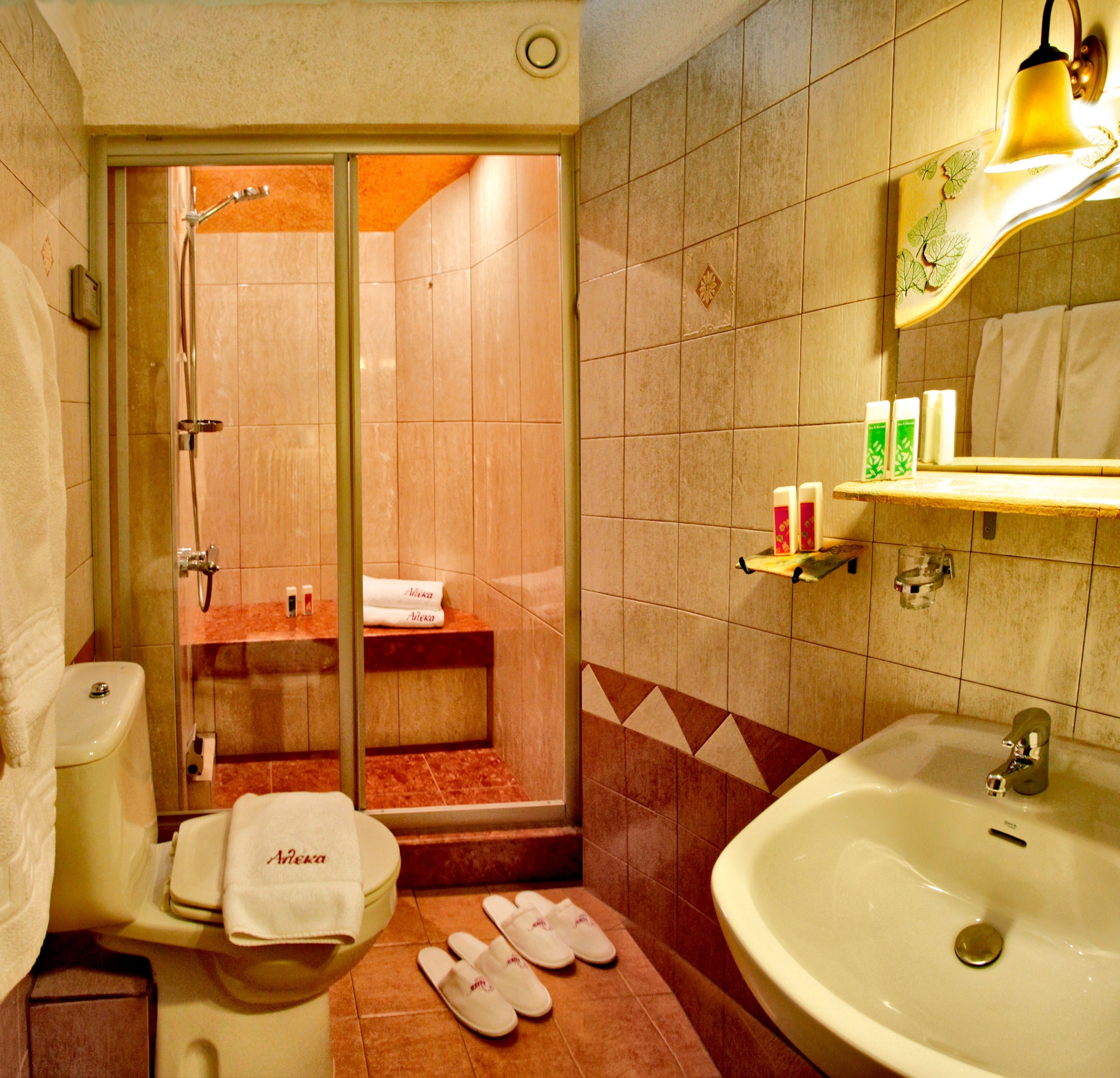 A bathroom with a shower, toilet, sink, and a towel rack.