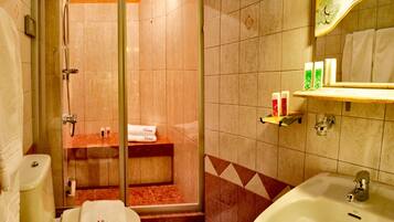 A bathroom with a shower, toilet, sink, and a towel rack.