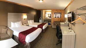 A hotel room with two beds, a sofa, a desk, a mirror, and a television. - Knights Inn Huntsville, ON (Huntsville)