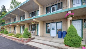 A motel with a two-story structure, a covered front porch with outdoor seating, and a visible staircase leading to the entrance. - Knights Inn Huntsville, ON (Huntsville)
