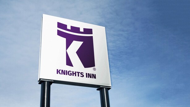 A Knights Inn sign with a knight's helmet and sword logo, mounted on a metal pole against a clear sky. - Knights Inn Huntsville, ON (Huntsville)