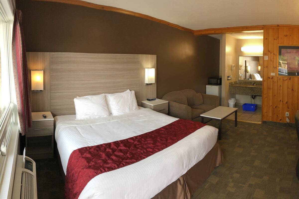 Une chambre d’hôtel avec un grand lit, des tables de chevet, un bureau, une chaise, un miroir et un téléviseur.