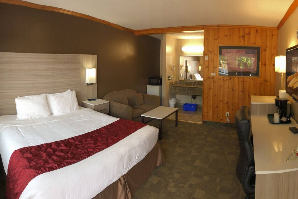 Une chambre d’hôtel équipée d’un lit, d’un bureau, d’une chaise, d’une télévision, d’un téléphone et d’une salle de bain.