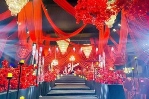 Un pasillo con cortinas rojas, candelabros y arreglos florales.