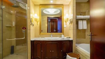 A bathroom with a glass shower enclosure, a vanity with a large mirror and wall sconces, a bathtub, and a towel rack.