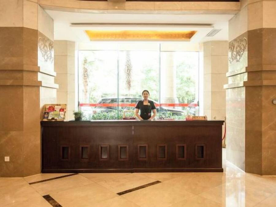 Una reception con una persona dietro, ampie finestre e pavimento piastrellato.