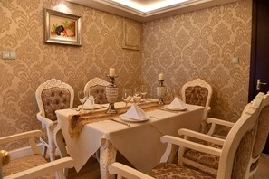 A dining room with a table set for four, ornate chairs, and a patterned wallpaper. - Xintian International Hotel (Xiangtan)