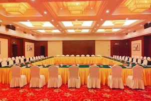 Un salón de conferencias con una mesa larga, sillas y un escenario.
