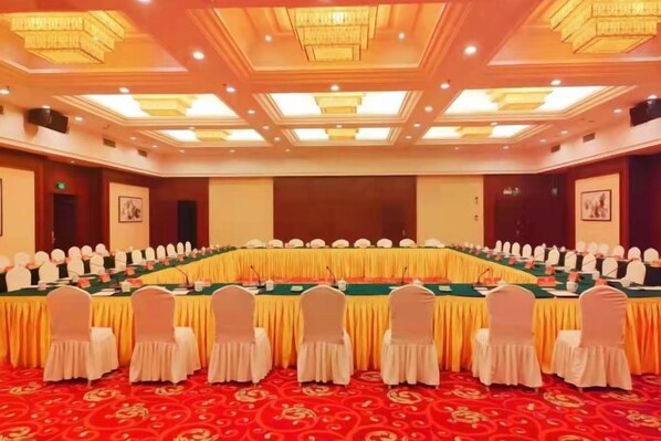 A conference room with a long table, chairs, and a stage.