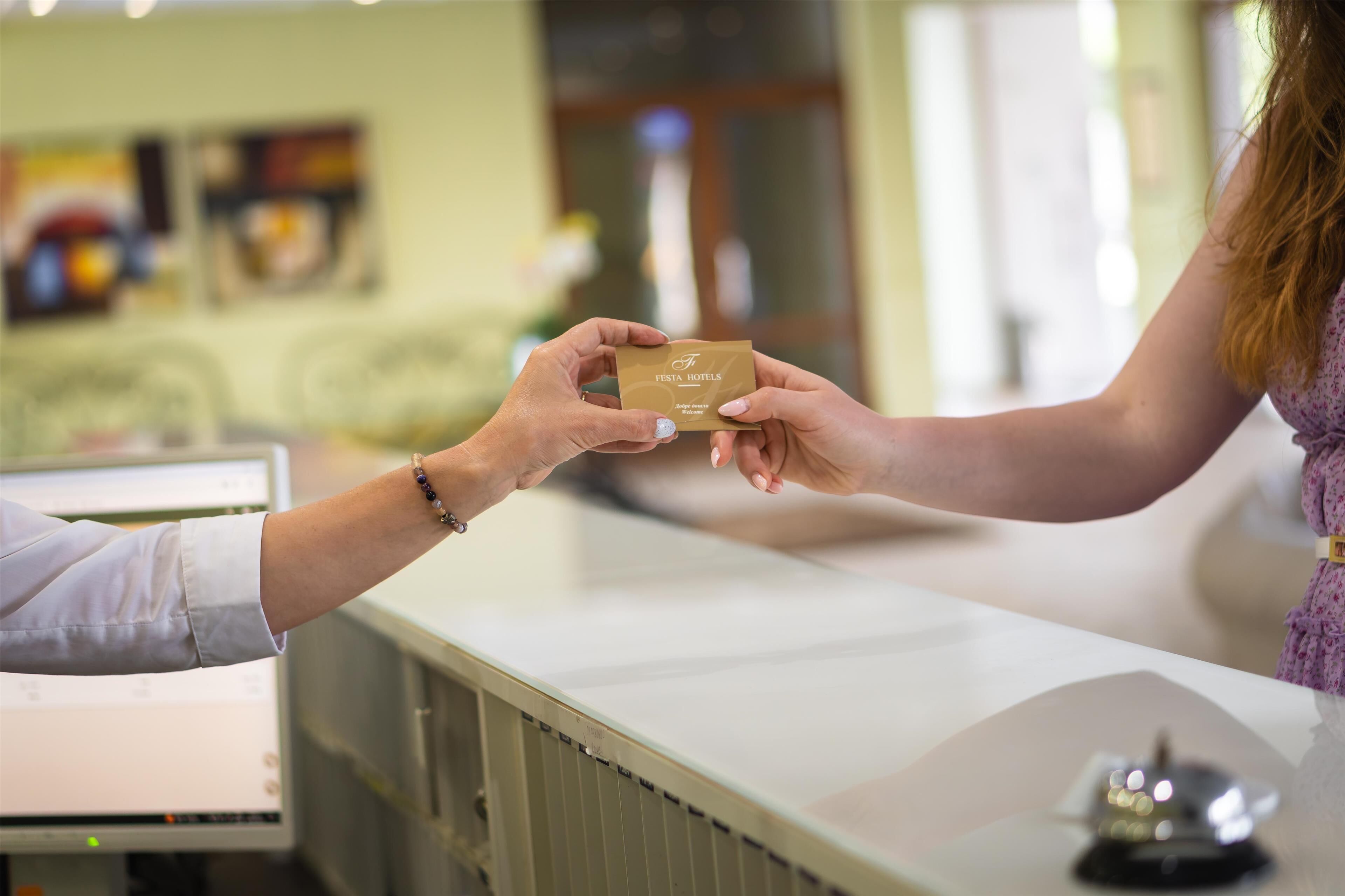 A person handing over a card to another person at a reception desk.