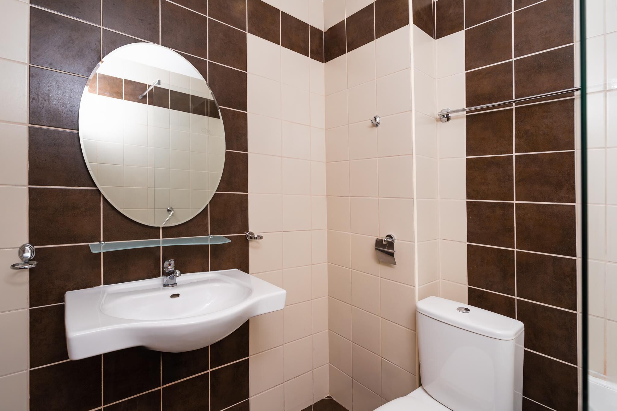 A bathroom with a white sink, a round mirror, and a toilet.