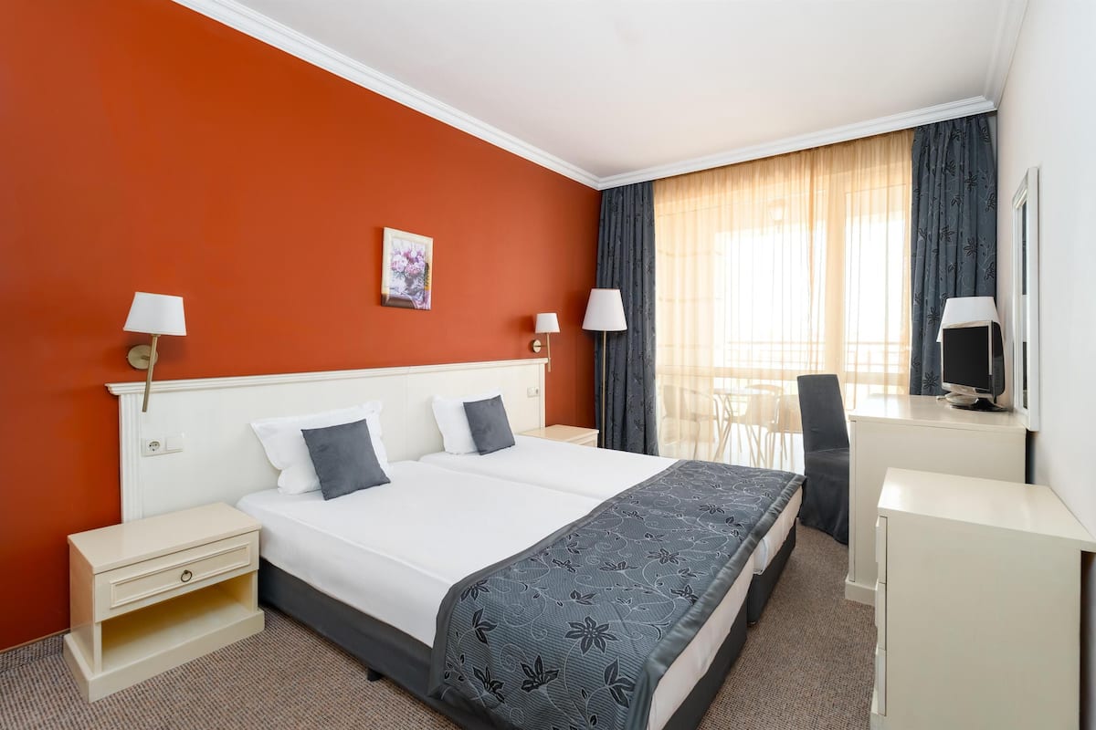 A hotel room with a large bed, two bedside tables, a desk, and a chair.