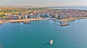 A coastal cityscape with a marina, residential buildings, and a boat in the water. - Hotel Festa Pomorie Resort (Pomorie)