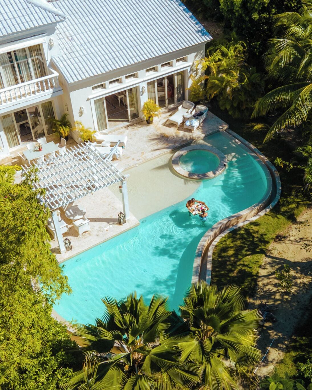 A resort with a large pool, lounge chairs, and palm trees.