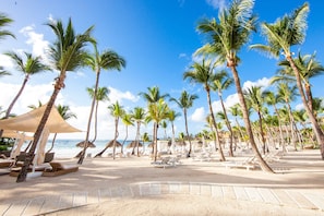 Privat strand, hvit sand, solsenger og parasoller