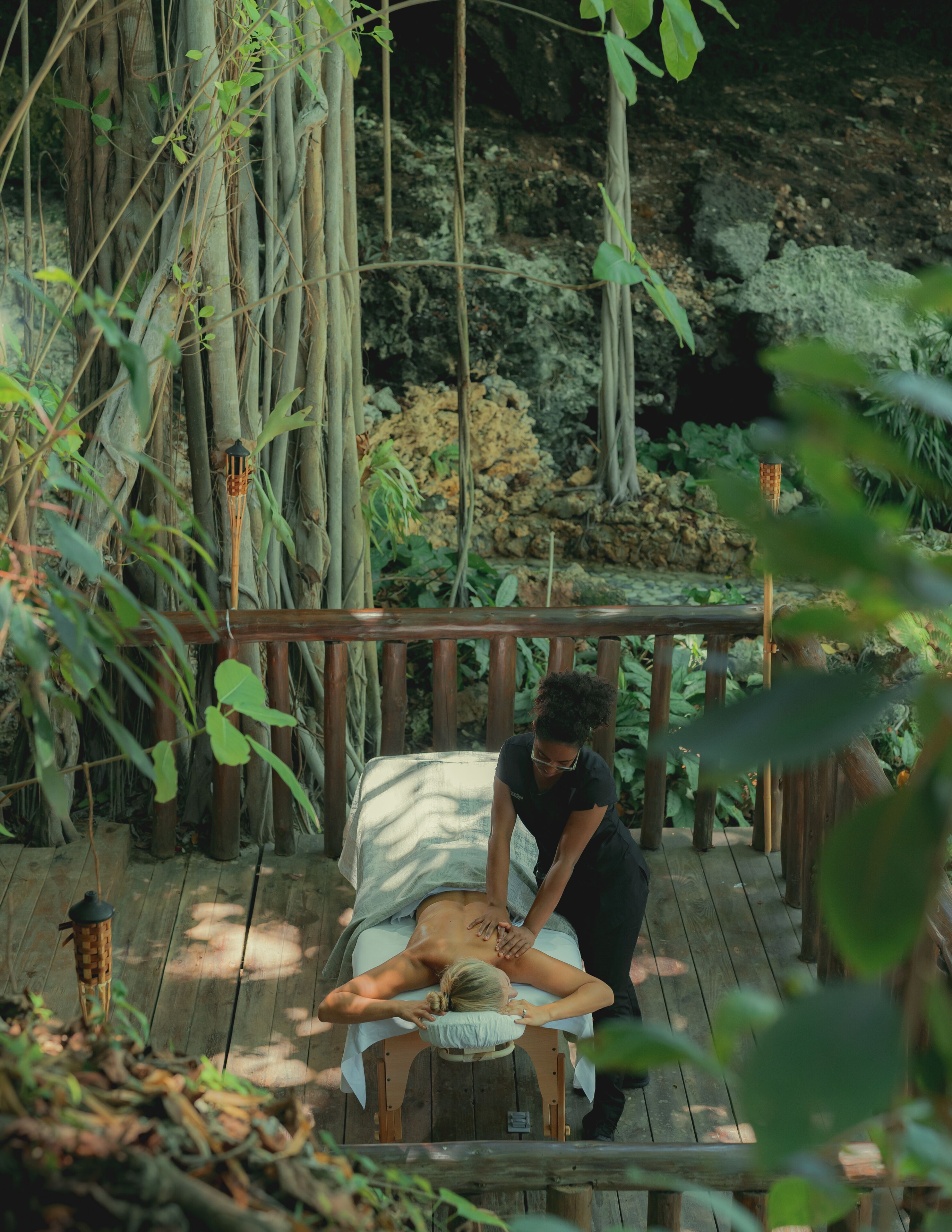 A wooden deck with a massage table and a person performing a massage.