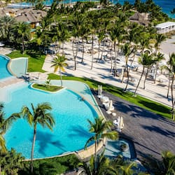 Relax by the infinity pool overlooking the ocean, surrounded by palm trees and sun loungers.