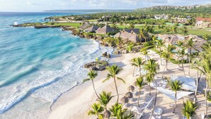 A coastal resort with beachfront villas, palm trees, and a golf course.